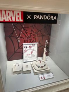 an assortment of jewelry on display in a glass case with spider - man's web