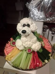 there is a plate with vegetables and a dog made out of cauliflowers