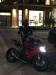 a man sitting on a motorcycle in front of a building at night with his helmet on