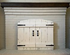 an old white painted fireplace with black handles