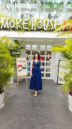 a woman standing in front of a store with lots of plants and potted plants