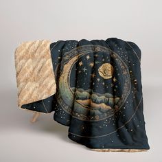 a blanket with an image of the moon and stars on it next to a pillow