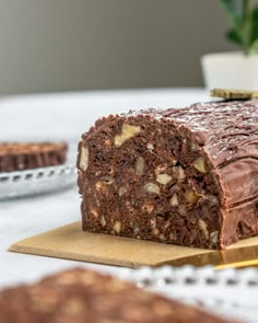 a piece of chocolate cake sitting on top of a cutting board next to some cookies