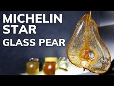 a glass pear hanging from the side of a kitchen counter with honey jars behind it