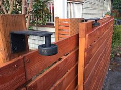 a wooden fence with an electronic device attached to the top and bottom part, in front of a house