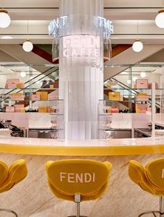 three yellow chairs sitting in front of a counter with the word fendi written on it