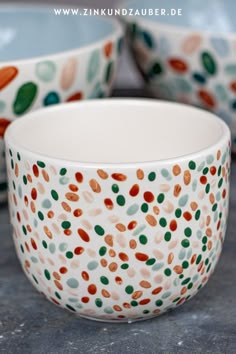 two bowls sitting on top of a table next to each other with different colored dots