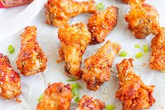 chicken wings with sauce and green onions on a white plate next to ketchup