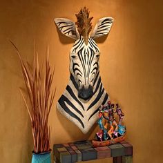 a zebra head mounted to the side of a wall next to a vase and plant