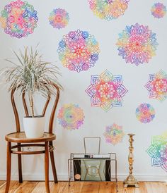 a room with a chair, potted plant and wallpaper on the wall that has colorful flowers