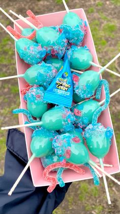 blue and green candy lollipops in a pink box with toothpicks