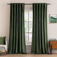 a green curtain hanging in front of a window next to a chair and side table