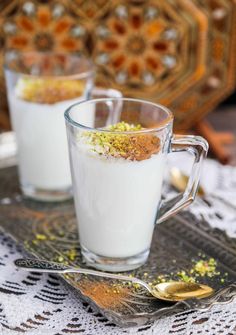 two glass mugs filled with food sitting on top of a doily covered table