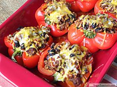 stuffed peppers with cheese and other toppings in a red casserole dish