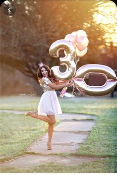 a woman in a white dress is holding balloons and the number thirty five on it