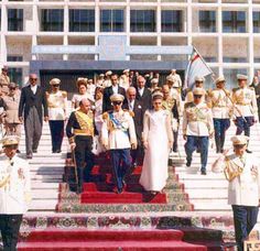 the queen and prince are walking down the steps in front of an official building with other people