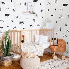 a baby's room with black and white wallpaper, a wooden crib, potted plant, and stuffed animals on the floor