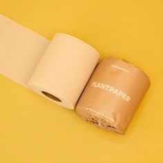 two rolls of toilet paper sitting next to each other on a yellow surface with the word plantpaper printed on it