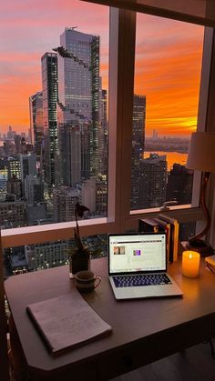 an open laptop computer sitting on top of a wooden desk in front of a window