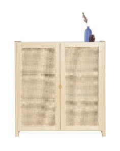 a white cabinet with two doors and a blue vase sitting on it's side