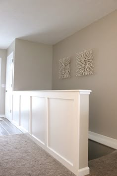 an empty living room with carpeted flooring and two white framed pictures on the wall