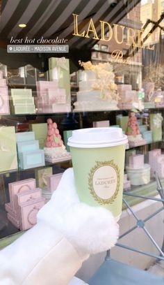 a cup of coffee sitting on top of a table in front of a store window