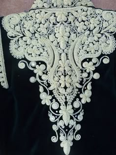 the back of a black dress with white embroidery on it