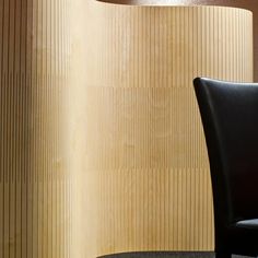 a black chair sitting in front of a wooden wall