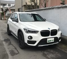 a white bmw suv is parked on the street