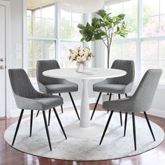 a white table with four grey chairs around it