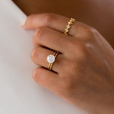 a woman's hand with two gold rings and a diamond ring on her finger