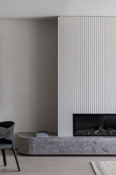 a living room with a fireplace, chair and television on the wall next to it