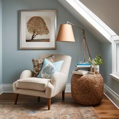 a living room with a chair, lamp and pictures on the wall in it's corner