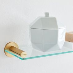 a glass shelf with a white container on it and a wooden block next to it