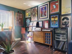 a room filled with lots of framed pictures and art on the wall next to a window