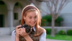 a woman holding a camera in front of her face while wearing a sweater and headband