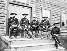 an old black and white photo of men in uniforms sitting on steps