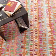 a table with books on top of it next to a coffee table and vase filled with flowers