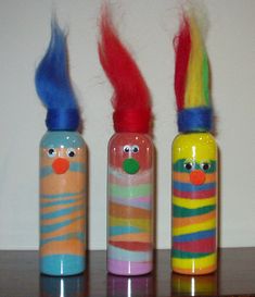 three colorful painted bottles with clown faces and hair on the top one has red, yellow, blue, green, and orange