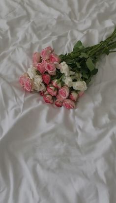 pink and white flowers are laid out on a bed