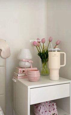 a white table topped with pink flowers next to a bed