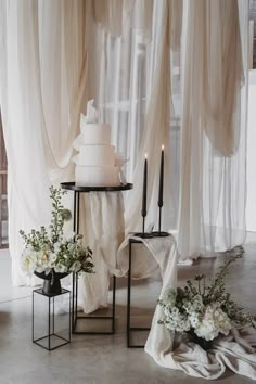 a wedding cake sitting on top of a table next to two vases filled with flowers