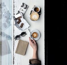 someone is holding their hand over a table with coffee and other items on it,