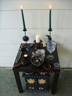 a table with candles and other items on it in front of a house or building