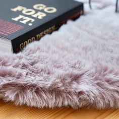 a book sitting on top of a wooden table next to a furry animal skin rug