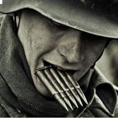 a man wearing a hat and holding a bunch of gold arrows in his mouth while looking at the camera