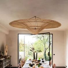 a dining room table with plates and bowls on it, in front of a large window