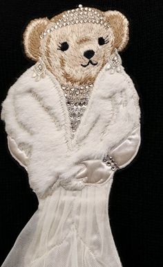 a teddy bear wearing a white dress and jacket