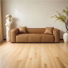 a living room scene with a couch and vase on the floor in front of a white wall