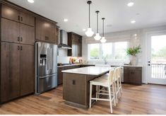 a large kitchen with wooden floors and stainless steel appliances in the center, along with white counter tops